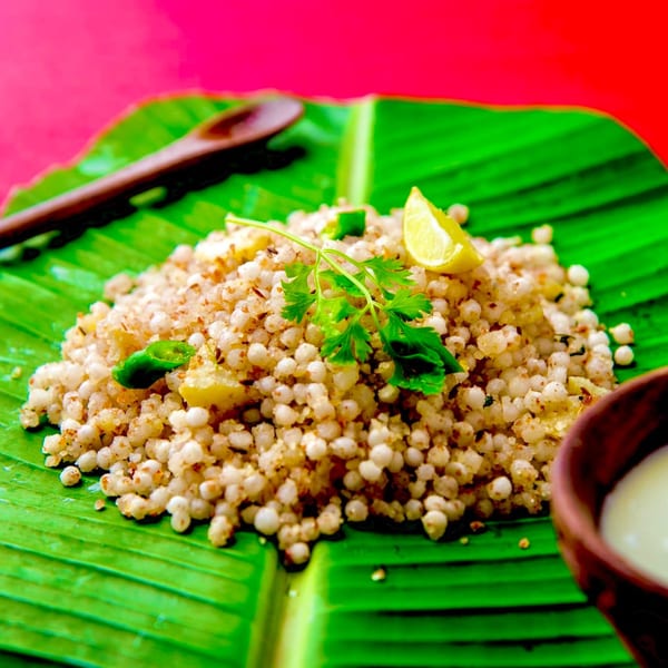 Sabudana Khichdi with cilantro, lime, and green chilies on a banana leaf, with a side of yogurt.