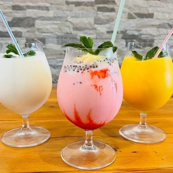 Three Indian drinks: white, pink with seeds, and yellow, garnished with mint and straws.